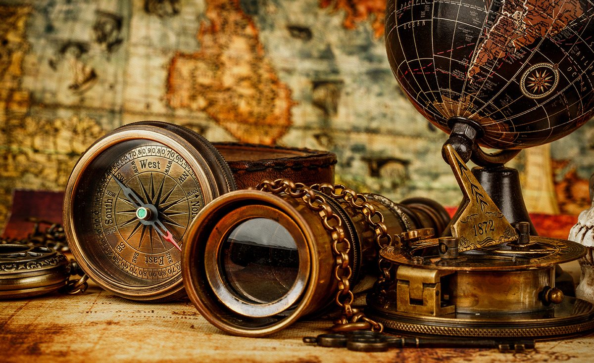 Antique globe, compass and binoculars on an old map