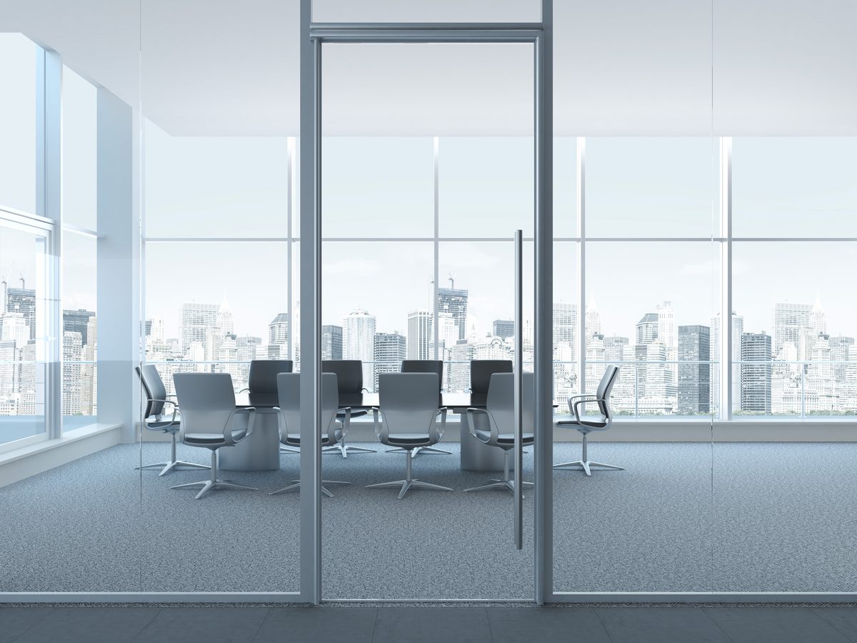 Empty glass-walled boardroom overlooking a city